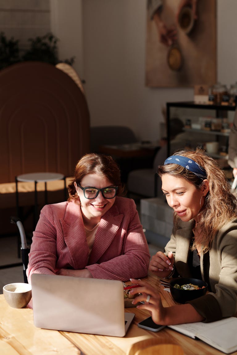 Two women collaborating on a project in a cozy café setting.