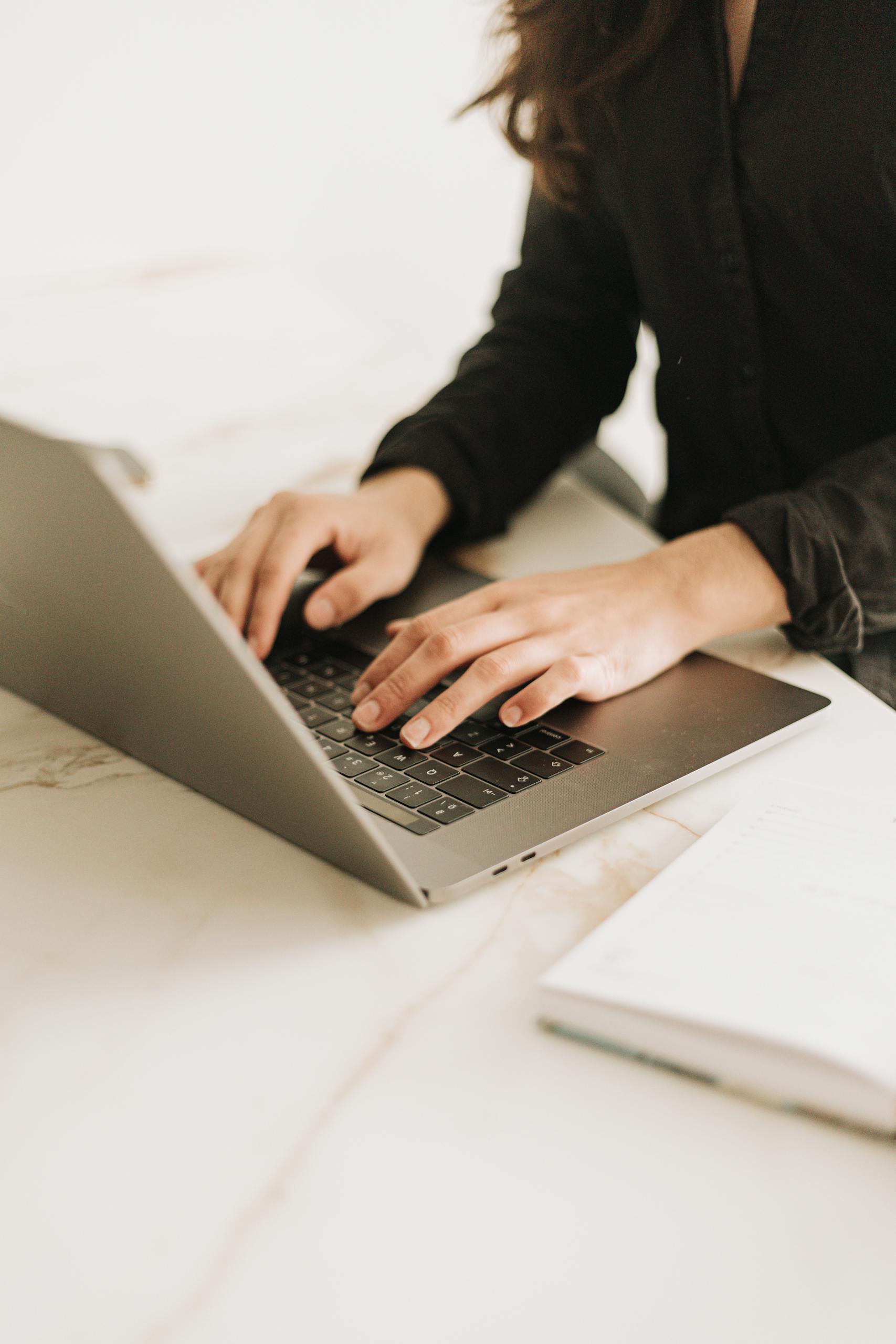 Woman typing on laptop in bright, modern workspace. Ideal for business settings.